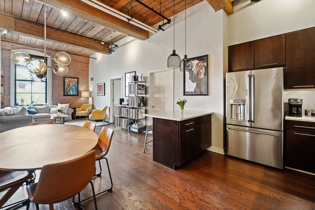 a kitchen with stainless steel appliances granite countertop a refrigerator a stove a sink a dining table and chairs with wooden floor