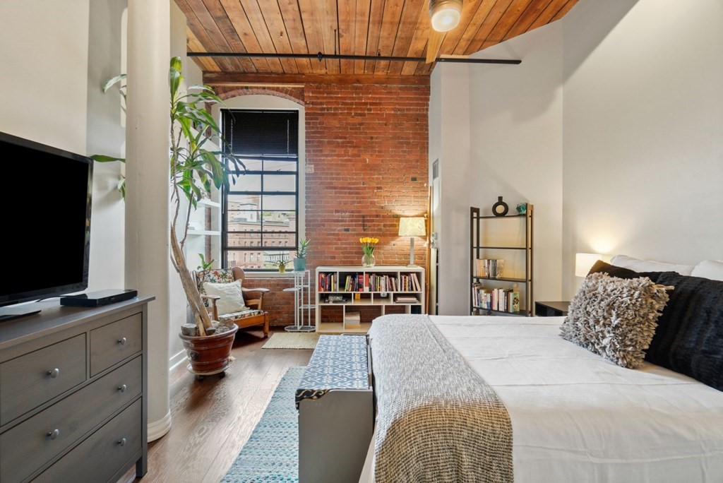 1245 Adams Street, Unit B210 Boston, MA 02124 - Photo 9 of 23 a bedroom with a bed and a flat tv screen on dresser