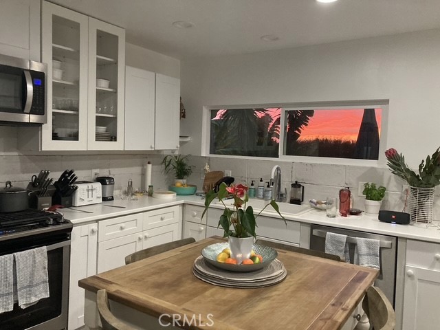 1570 Burgundy Road Encinitas, CA 92024 - Photo 35 of 47 a kitchen with a stove a microwave and dining table with wooden floor