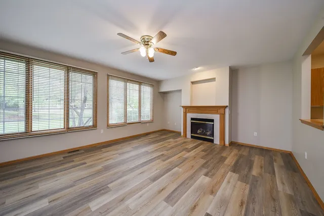 a view of an empty room with wooden floor fireplace and a window