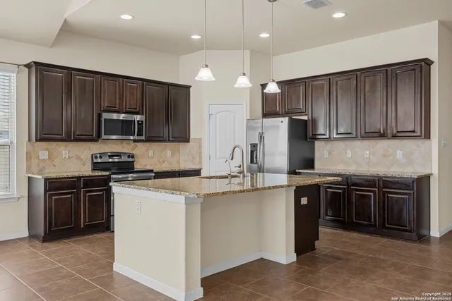 a kitchen with stainless steel appliances granite countertop wooden cabinets a stove a sink and dishwasher