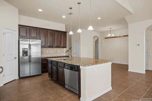 a kitchen with stainless steel appliances granite countertop a sink a stove and a refrigerator