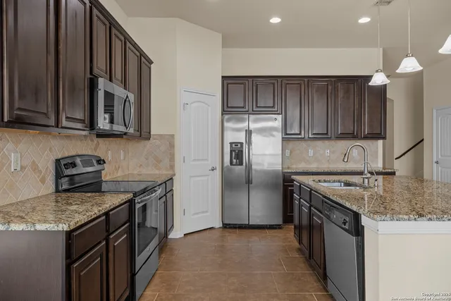 a kitchen with stainless steel appliances granite countertop a sink stove and refrigerator