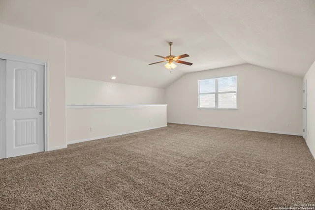 an empty room with windows and chandelier fan