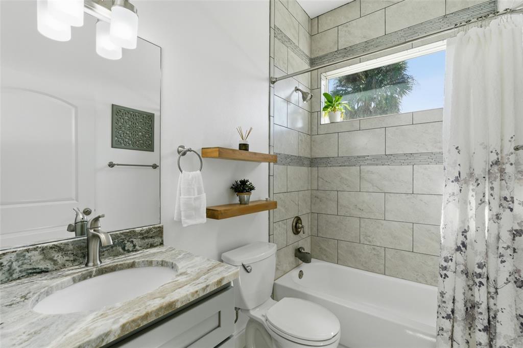 4437 Meridian Road Venice, FL 34293 - Photo 27 of 37 a bathroom with a granite countertop bathtub sink vanity mirror and toilet