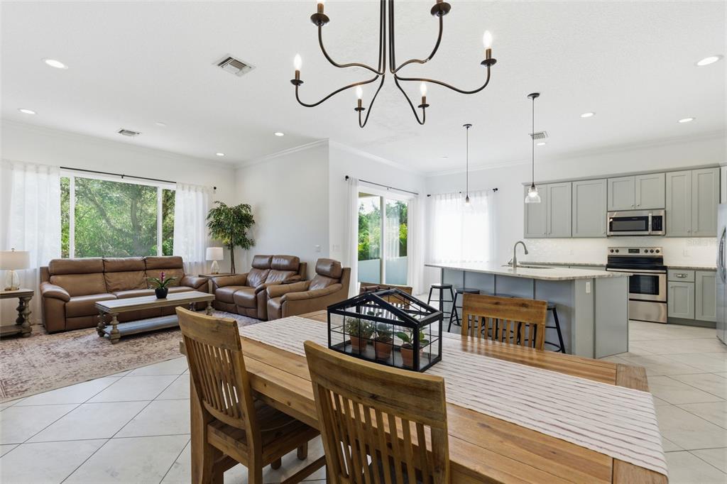 4437 Meridian Road Venice, FL 34293 - Photo 9 of 37 a open kitchen with stainless steel appliances granite countertop a stove a refrigerator a kitchen island a dining table and chairs with wooden floor