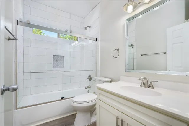 a bathroom with a granite countertop bathtub shower sink vanity and toilet