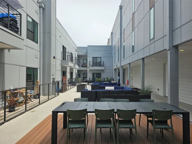 a view of a roof deck with table and chairs a barbeque with wooden floor and fence