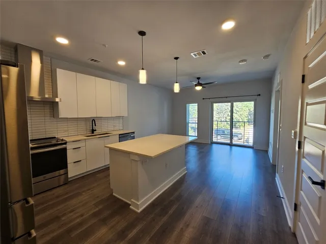 a large kitchen with cabinets wooden floor and stainless steel appliances