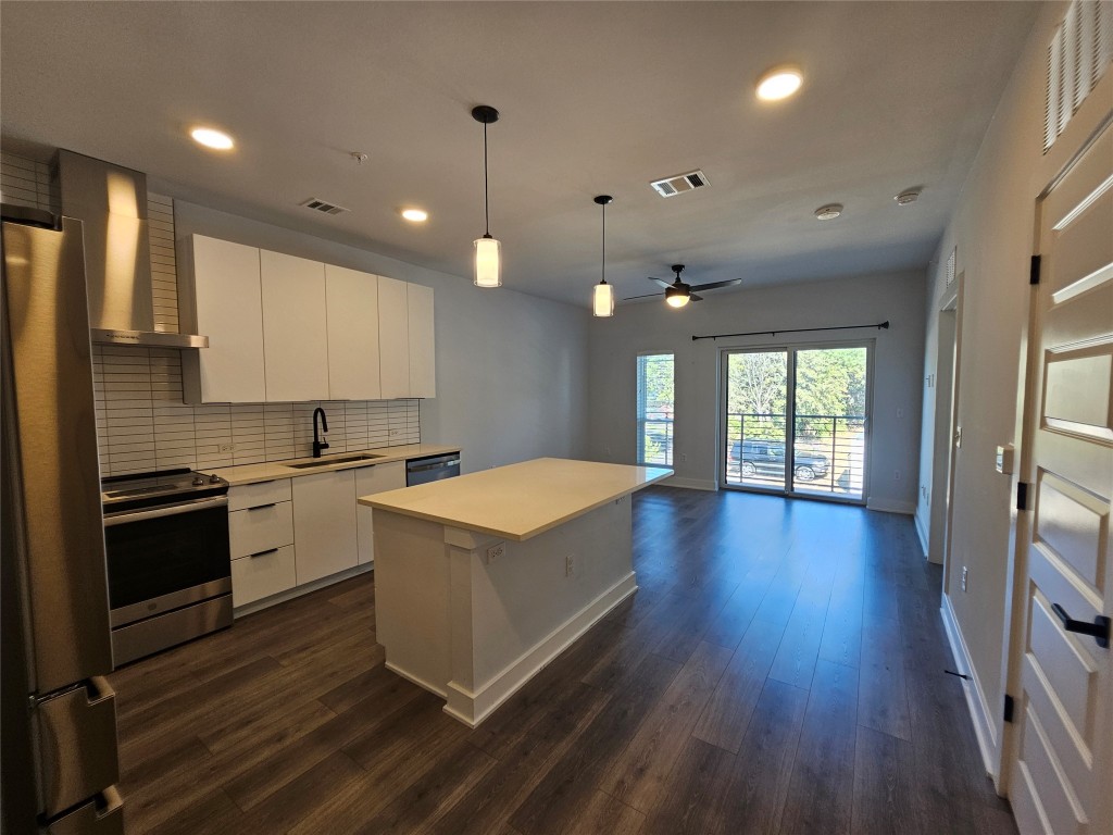 2220 Webberville Road, Unit 310 Austin, TX 78702 - Photo 6 of 39 a large kitchen with cabinets wooden floor and stainless steel appliances