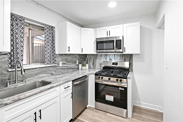 a kitchen with cabinets stainless steel appliances a sink and a stove