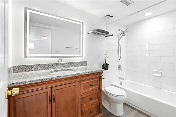a bathroom with a granite countertop toilet sink and mirror