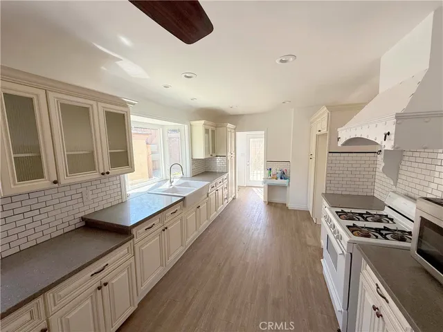 a large kitchen with stainless steel appliances granite countertop a lot of counter space and wooden floors