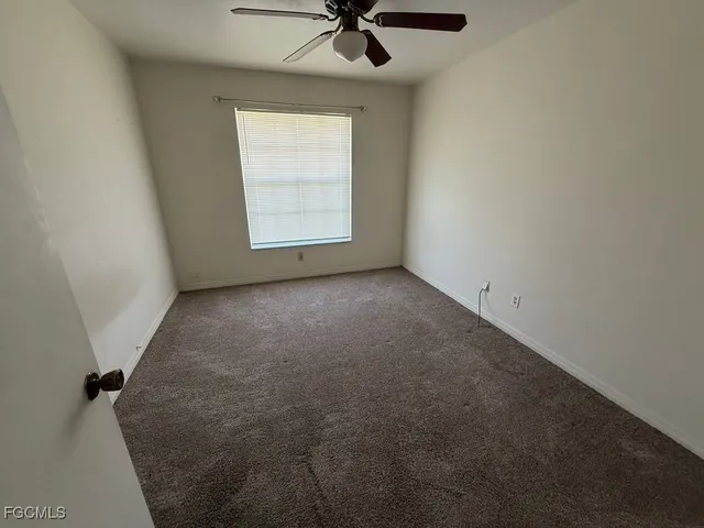 an empty room with a window and a ceiling fan