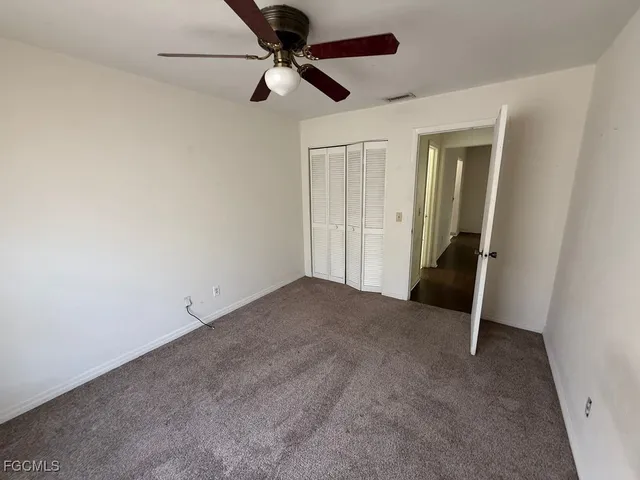 an empty room with a ceiling fan and carpet