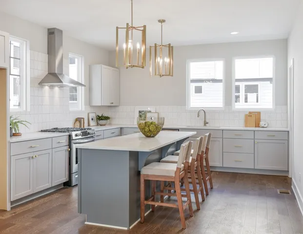 a kitchen with a sink white cabinets and wooden floor