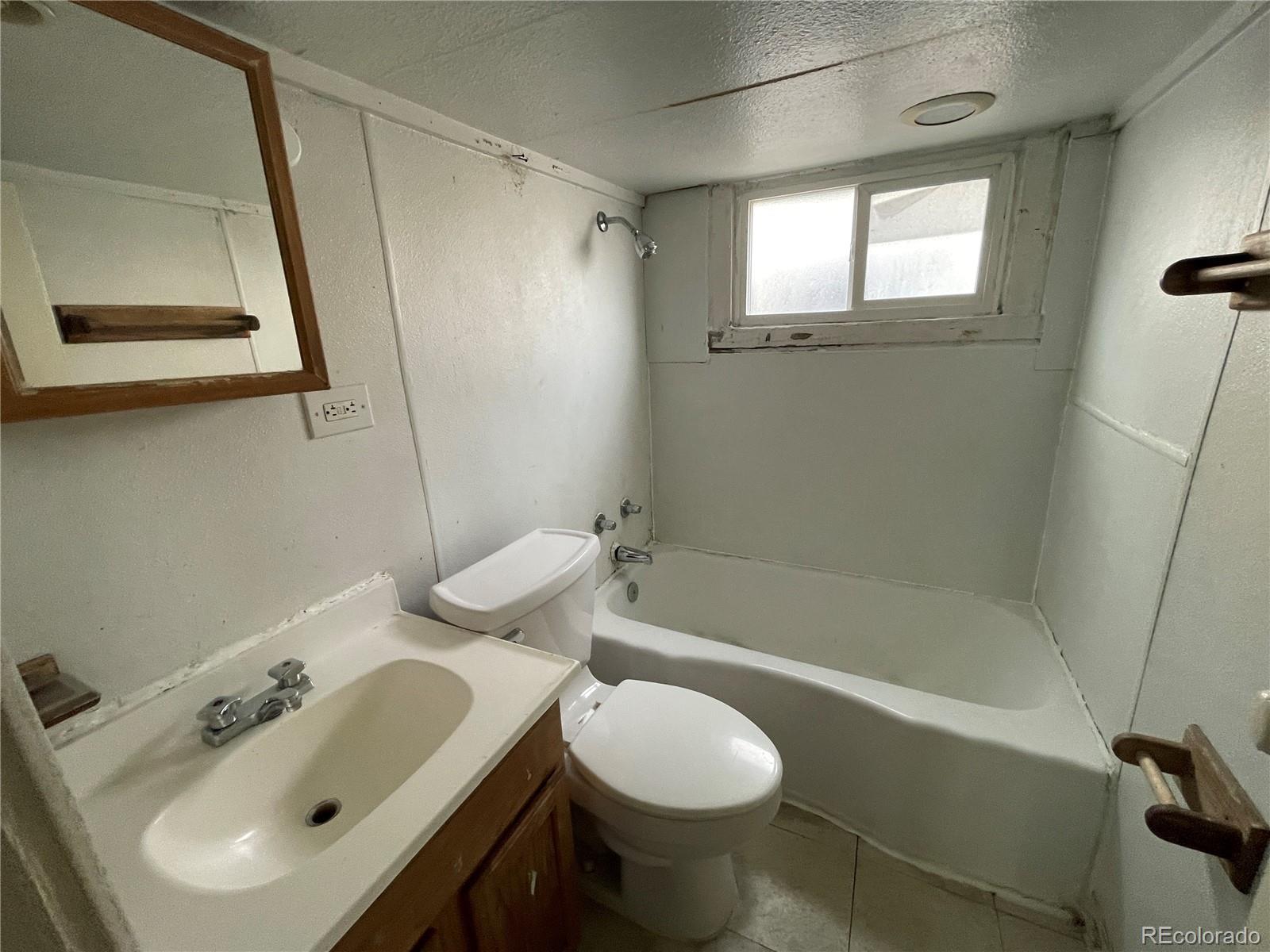 4941 Sherman Street, Unit B Denver, CO 80216 - Photo 13 of 14 a bathroom with a sink mirror toilet and bathtub