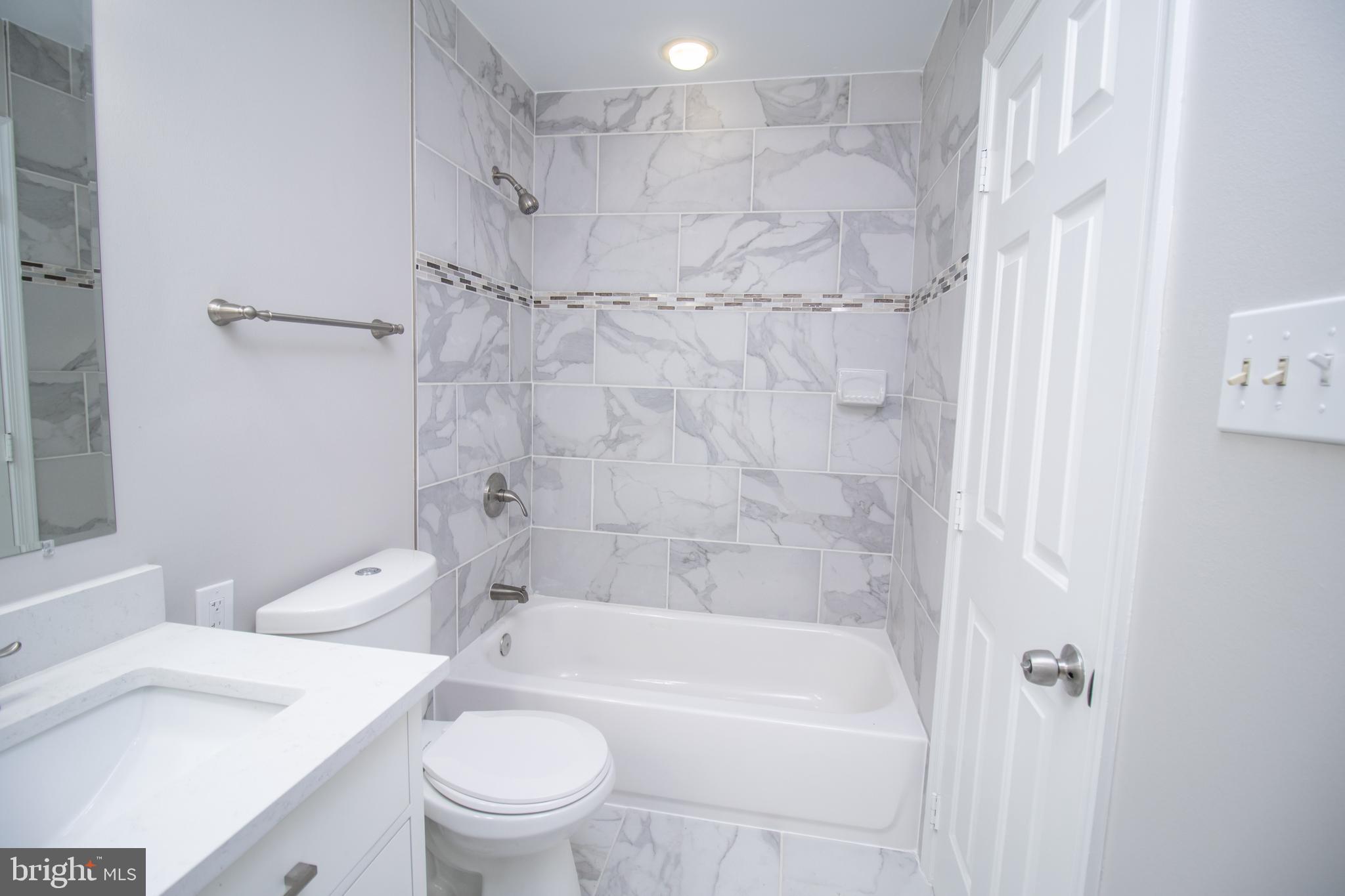 7708 Scatteree Road Severn, MD 21144 - Photo 30 of 41 a bathroom with a bathtub shower sink vanity and toilet