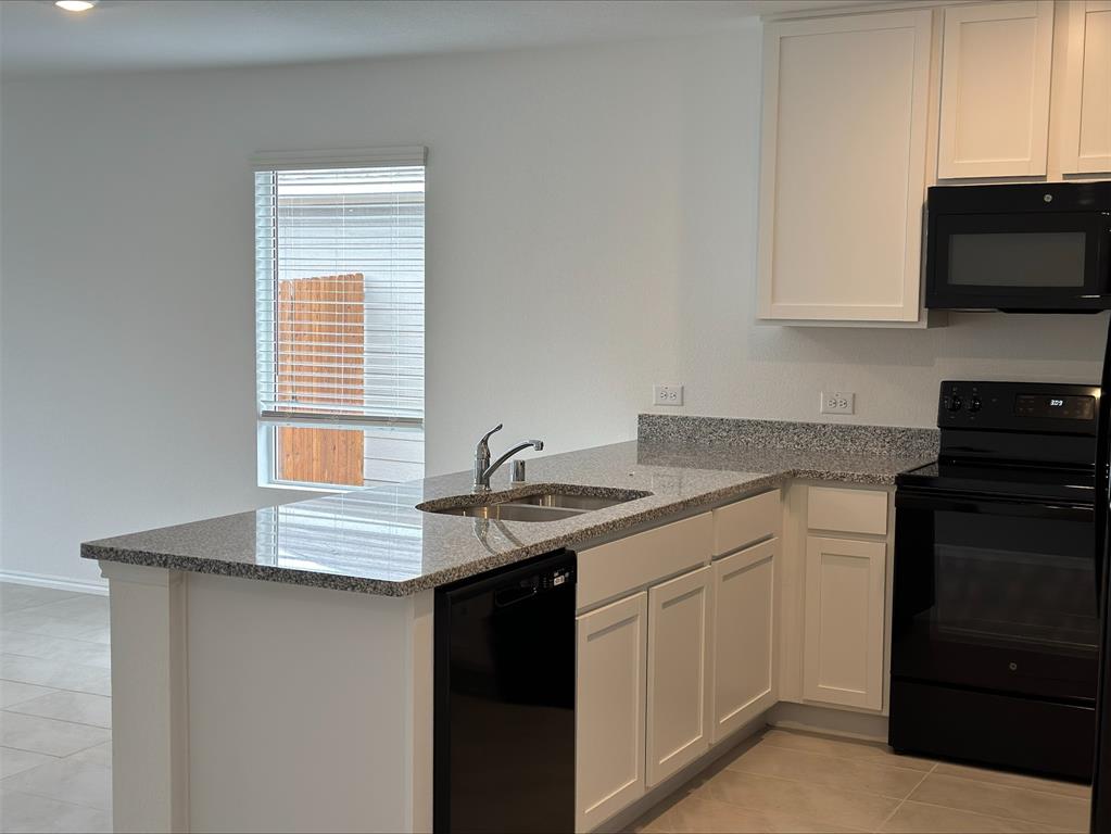 320 Dewberry Street Princeton, TX 75407 - Photo 13 of 19 a kitchen with stainless steel appliances granite countertop a sink dishwasher a stove and a microwave oven with cabinets