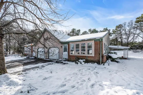a front view of a house with a yard covered with snow