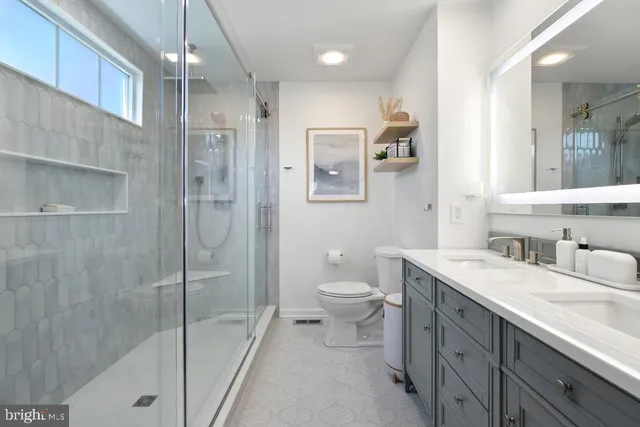 a bathroom with a granite countertop sink a toilet a shower and a mirror