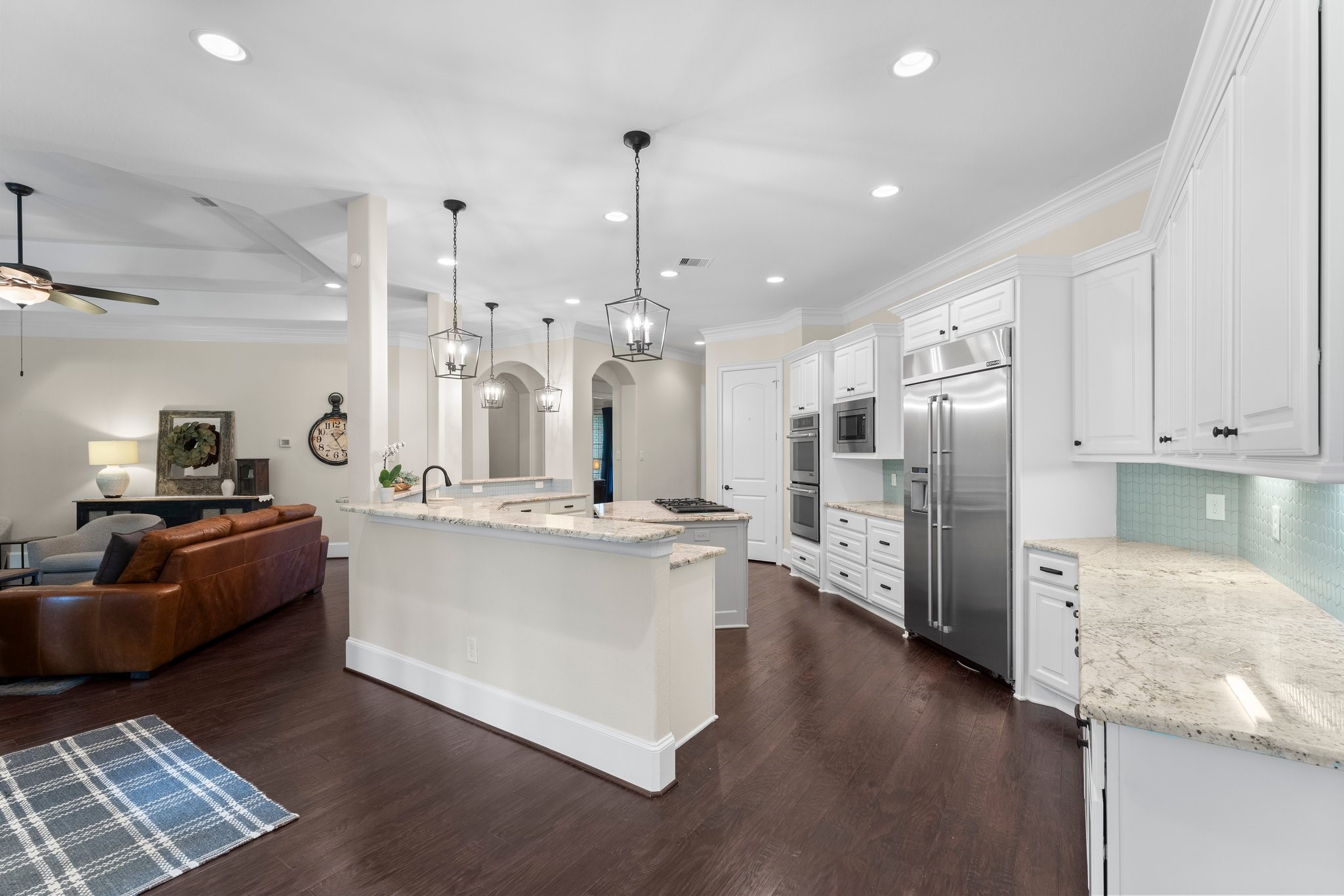 5006 Newport Court Spring, TX 77386 - Photo 18 of 46 a large kitchen with stainless steel appliances kitchen island granite countertop a large kitchen island a stove a refrigerator a sink a dining table and chairs with wooden floor