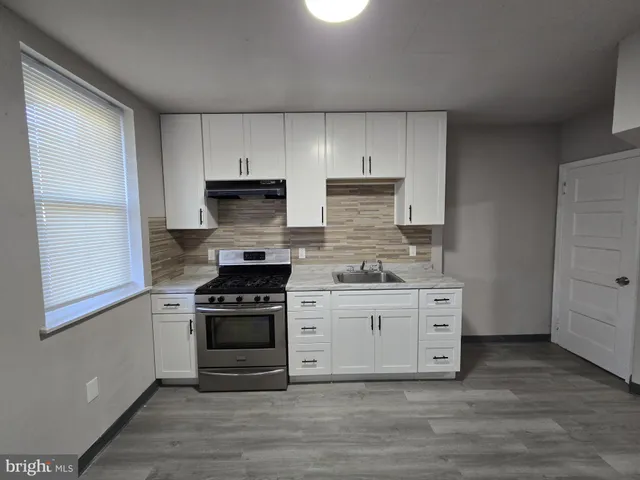 a kitchen with stainless steel appliances white cabinets and a stove top oven