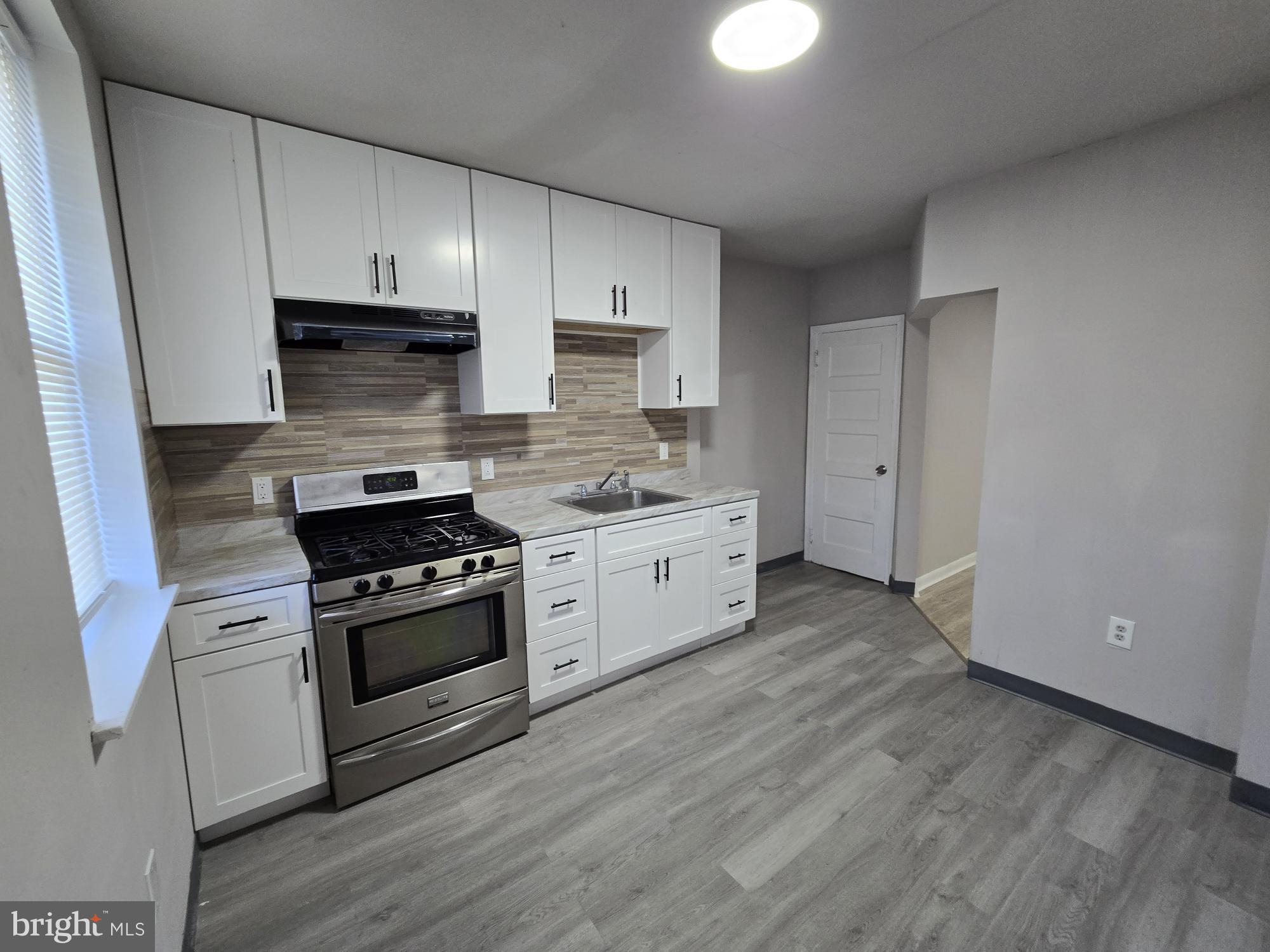 5140 North Fairhill Street Philadelphia, PA 19120 - Photo 7 of 24 a kitchen with stainless steel appliances white cabinets and a stove top oven