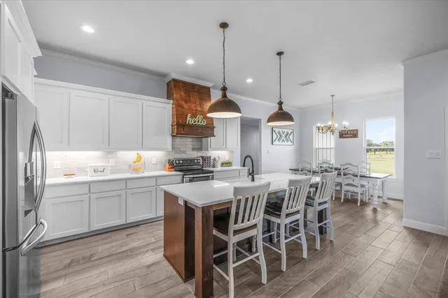 a kitchen with stainless steel appliances kitchen island granite countertop a table chairs and a stove