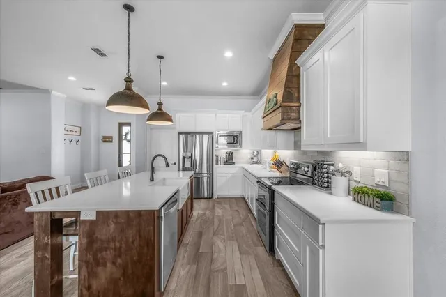 a kitchen with stainless steel appliances granite countertop a sink a stove and a wooden floors