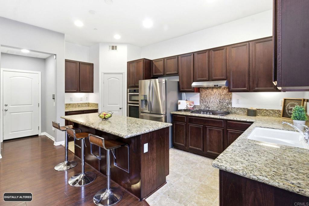 1508 Carpinteria Street Chula Vista, CA 91913 - Photo 11 of 39 a kitchen with stainless steel appliances granite countertop a table chairs sink refrigerator and microwave