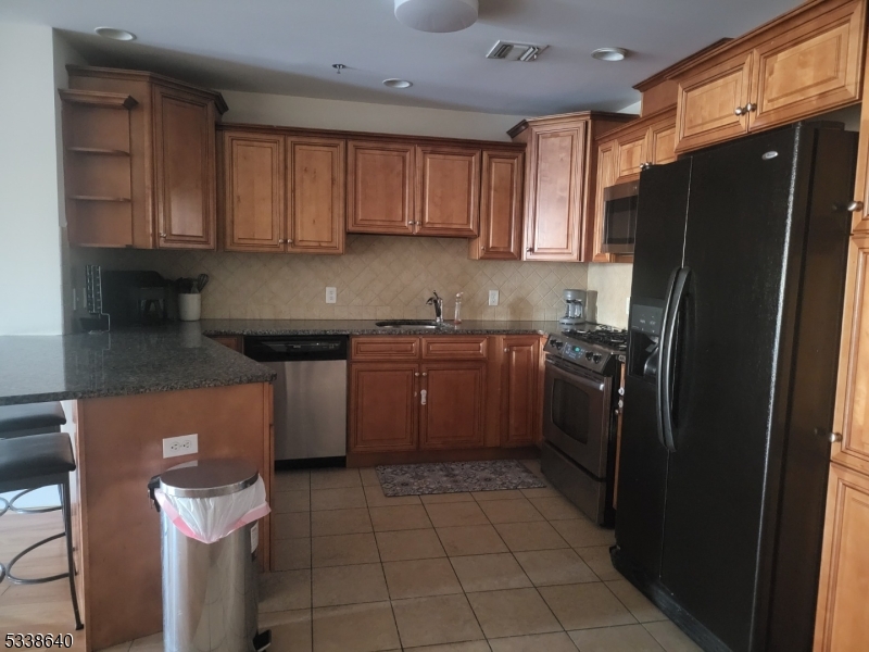115 Ferry Street, Unit 3A Newark, NJ 07105 - Photo 3 of 10 a kitchen with stainless steel appliances granite countertop a refrigerator a sink a stove a microwave and island