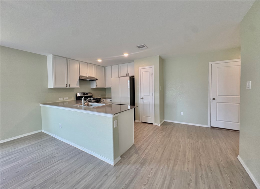 1109 Demeter Drive Portland, TX 78374 - Photo 5 of 18 a kitchen with wooden floors and white cabinets