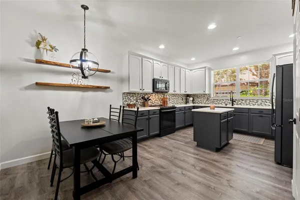 a kitchen with a table chairs a sink dishwasher refrigerator and cabinets