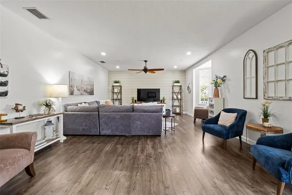 a living room with furniture kitchen view and a wooden floor