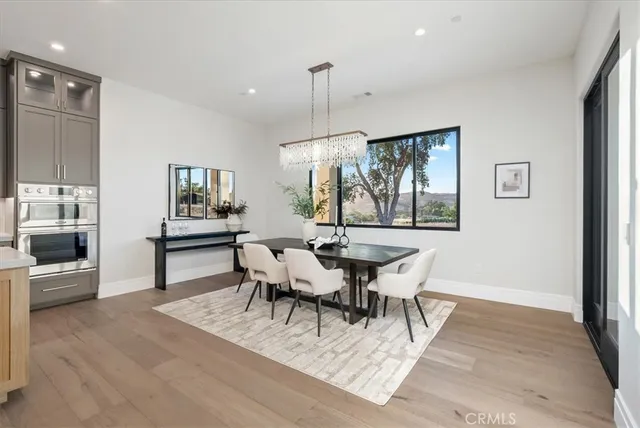 a view of a dining room and livingroom with furniture wooden floor a chandelier