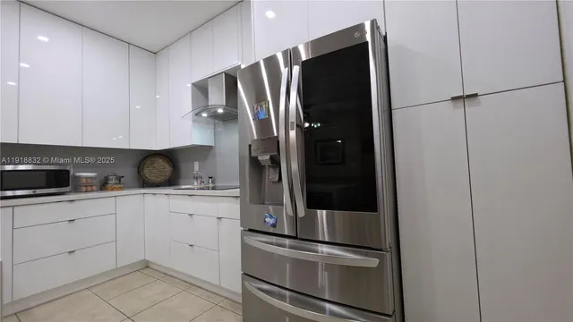 a kitchen with a sink dishwasher and white cabinets with wooden floor