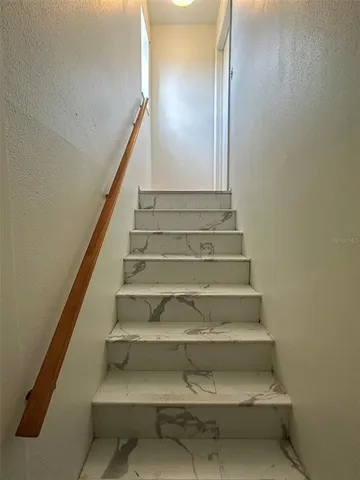 a view of an empty room with chandelier fan and kitchen view
