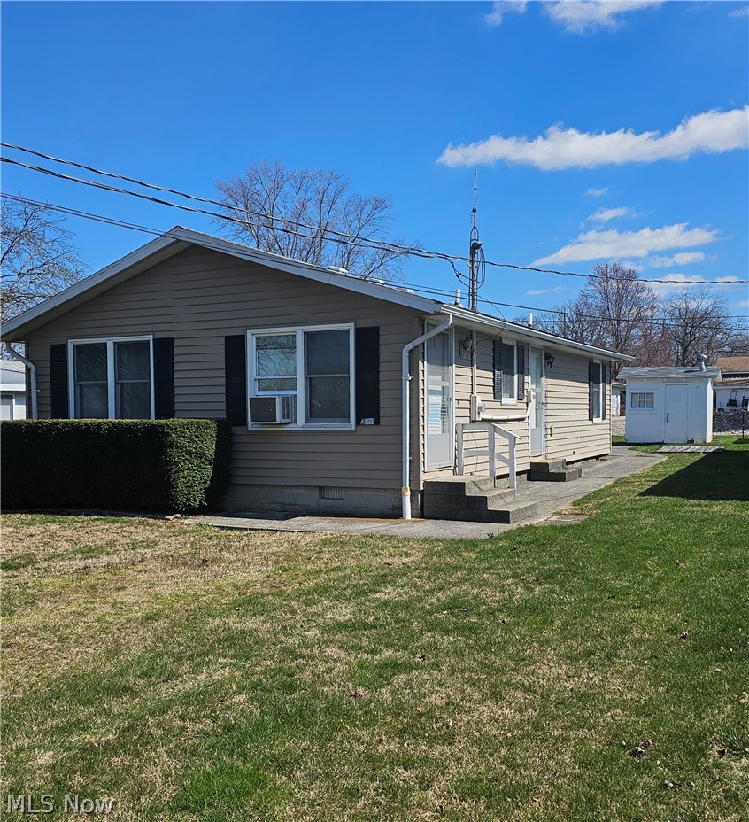 Back of property featuring a yard, a patio, and a storage shed
