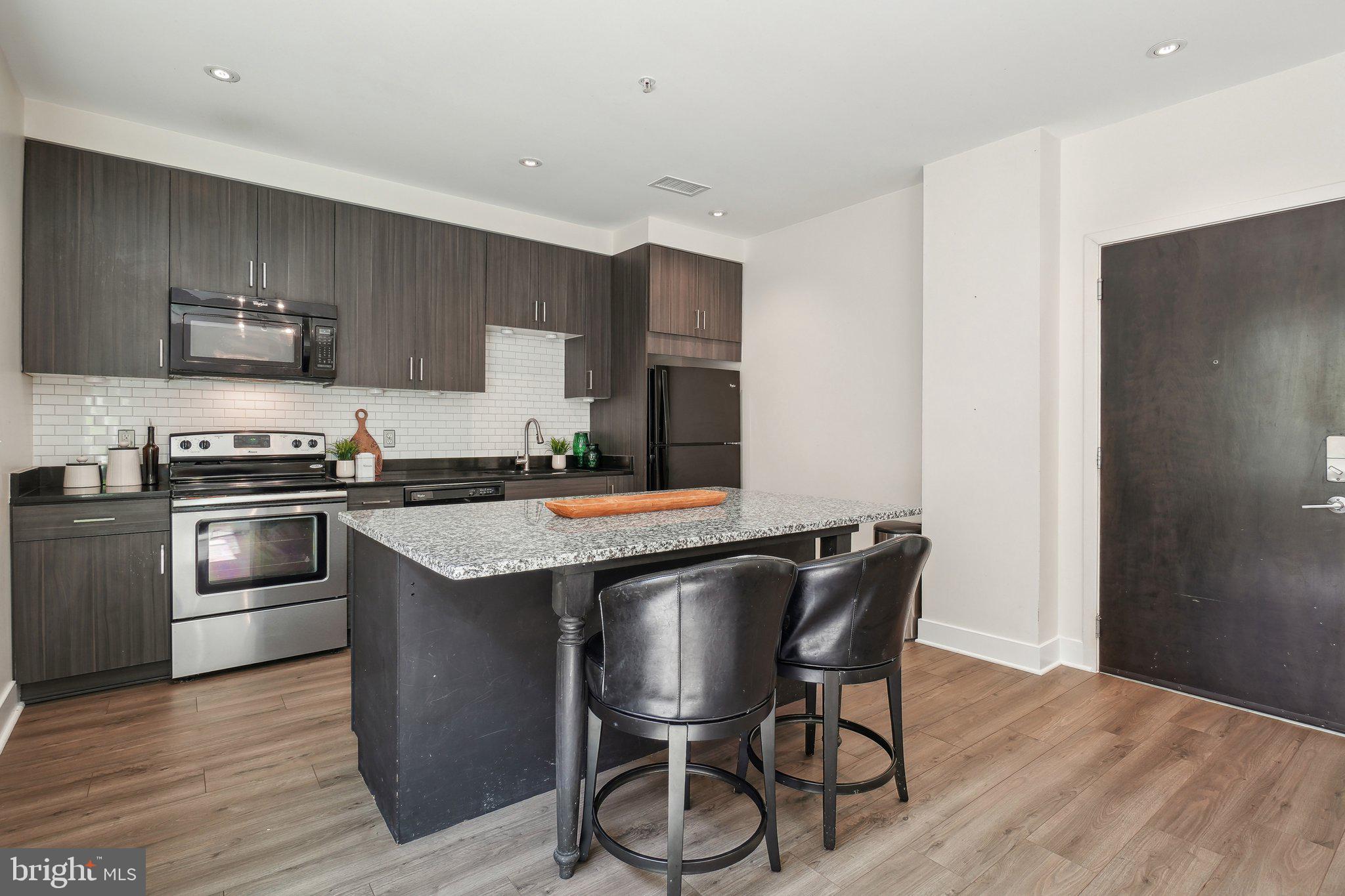 2550 17th Street Northwest, Unit 205 Washington, DC 20009 - Photo 3 of 25 a kitchen with stainless steel appliances a table chairs refrigerator and microwave