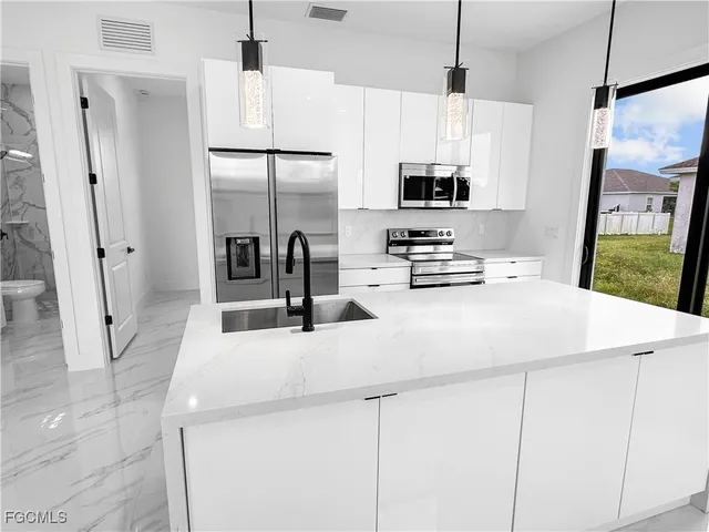 a kitchen with stainless steel appliances a refrigerator a sink a stove a microwave and cabinets