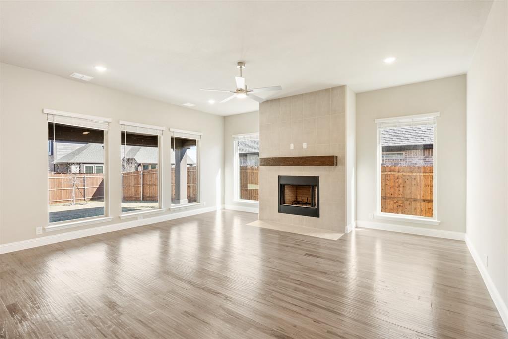 1004 Stonehaven Drive Justin, TX 76247 - Photo 11 of 35 an empty room with wooden floor fireplace and windows