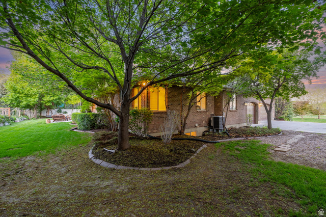 6208 West Bull River Road Highland, UT 84003 - Photo 81 of 90 Brick exterior with arched garage door, mature trees, and established landscaping with stone edging