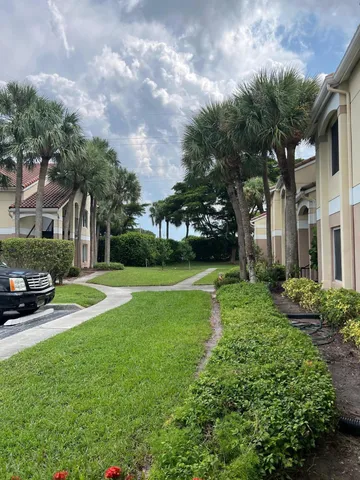 a view of a house with a big yard plants and large trees