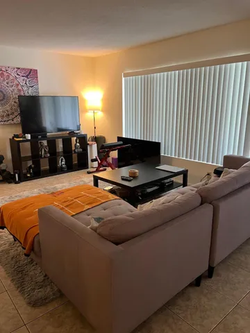 a living room with furniture a flat screen tv and a window