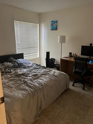 a bedroom with a bed and a computer on the desk