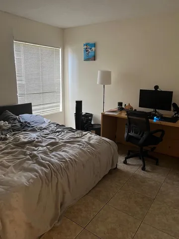 a bedroom with a bed and a computer on the desk