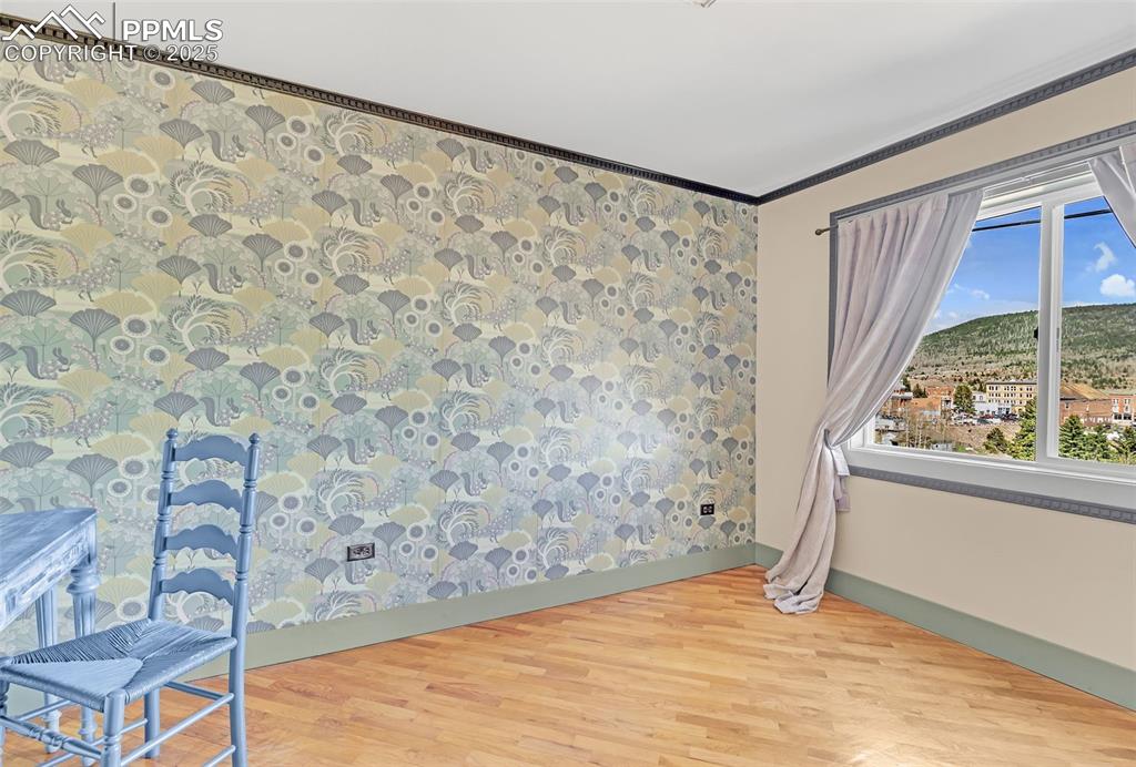 123 7th Street Victor, CO 80860 - Photo 22 of 50 Bedroom featuring light wood-style flooring, baseboards, plenty of natural light, crown molding, and wallpapered walls