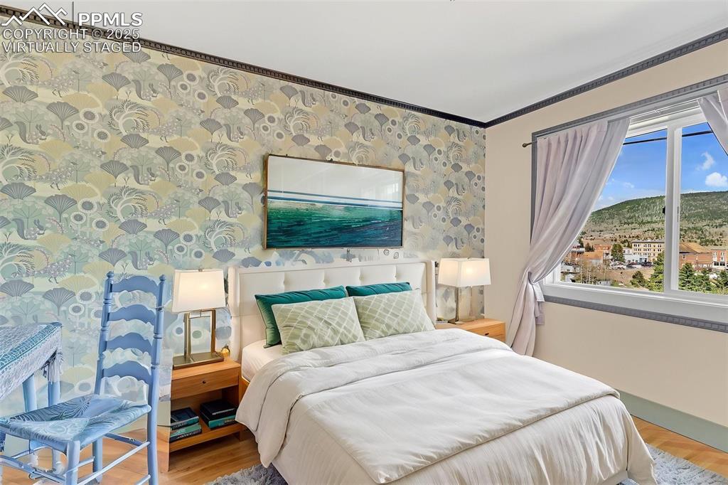 123 7th Street Victor, CO 80860 - Photo 23 of 50 Virtually Staged Bedroom featuring light wood-style flooring, baseboards, plenty of natural light, crown molding, wallpapered walls and great views of Town Center.