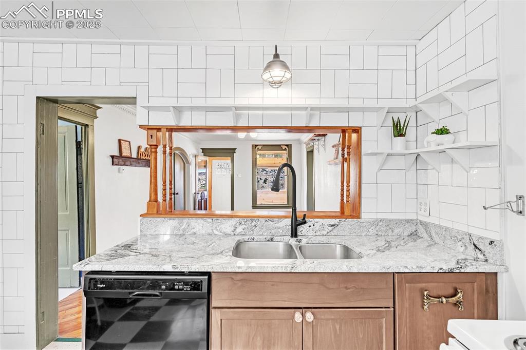123 7th Street Victor, CO 80860 - Photo 28 of 50 Kitchen with black dishwasher, a sink, open shelves, light stone counters and tile work